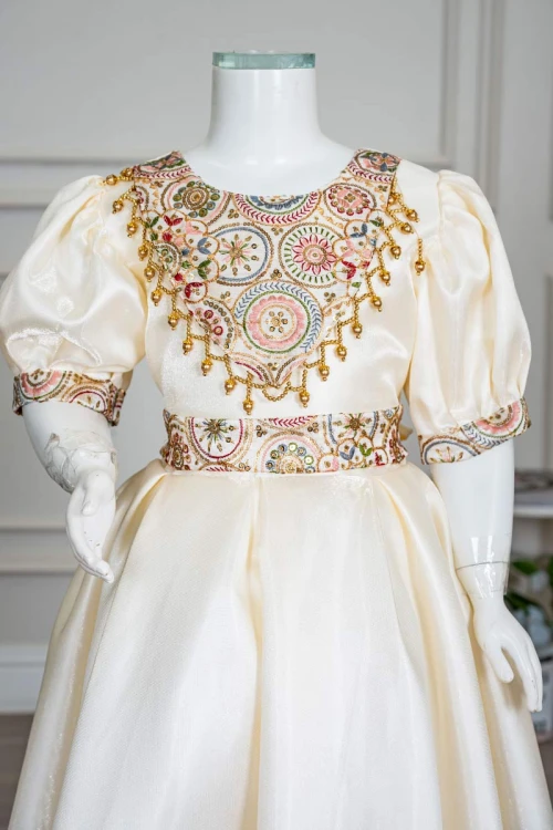 فستان بناتي طويل لون بيج فاتح مزين بتطريز ملون من الياقة و أطراف الأكمام و بحزام في الخصر