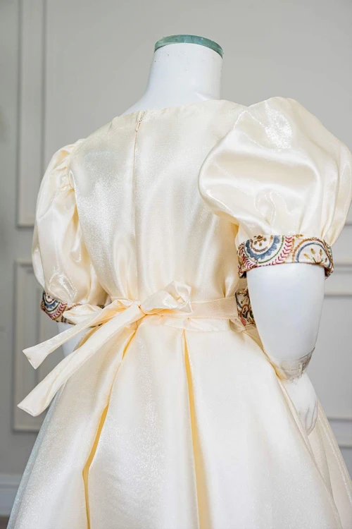 فستان بناتي طويل لون بيج فاتح مزين بتطريز ملون من الياقة و أطراف الأكمام و بحزام في الخصر