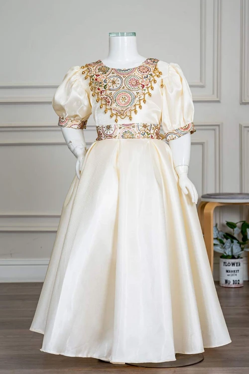 فستان بناتي طويل لون بيج فاتح مزين بتطريز ملون من الياقة و أطراف الأكمام و بحزام في الخصر