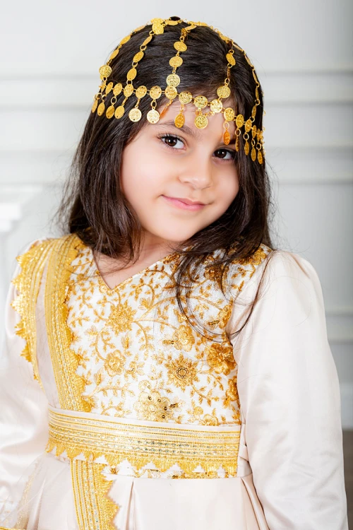 فستان تراثي بناتي لون بيج مزين بتطريز تراثي لون ذهبي ياقة قصة سبعة بأكمام طويلة و برباط في الخصر