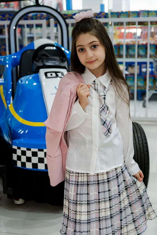 طقم بناتي من 3 قطع قميص أبيض بياقة مطوية و كرفته و أزرار من الأمام مع جاكيت باللون الوردي و تنورة كاروهات مع حزام أسود