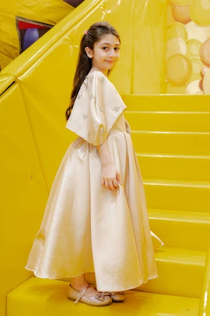 فستان بناتي لون بيج ياقة دائرية بدون أكمام مع فيونكة من الأمام و رباط في الخصر و بكاب علوي منفصل على الكتف مزين بفصوص الكريستال  