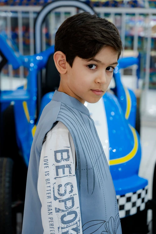 طقم ولادي 3 قطع بلوفر أبيض بكتابات و جاكيت سماوي بياقة عالية بدون أكمام مزين بزخارف مع بنطلون أسود طويل