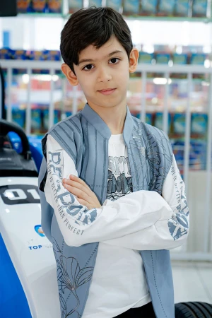 طقم ولادي 3 قطع بلوفر أبيض بكتابات و جاكيت سماوي بياقة عالية بدون أكمام مزين بزخارف مع بنطلون أسود طويل 