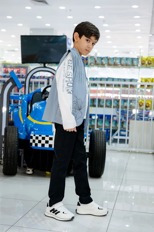 طقم ولادي 3 قطع بلوفر أبيض بكتابات و جاكيت سماوي بياقة عالية بدون أكمام مزين بزخارف مع بنطلون أسود طويل