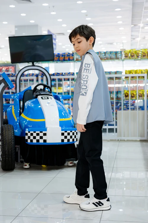 طقم ولادي 3 قطع بلوفر أبيض بكتابات و جاكيت سماوي بياقة عالية بدون أكمام مزين بزخارف مع بنطلون أسود طويل