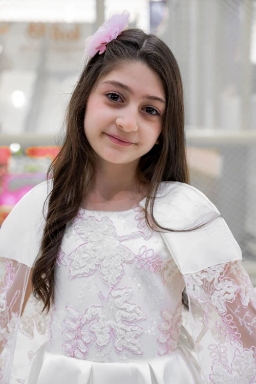 فستان بناتي لون أبيض ياقة دائرية بدون أكمام مزين بزهور و بوشاح تل منفصل على الكتف و برباط في الخصر