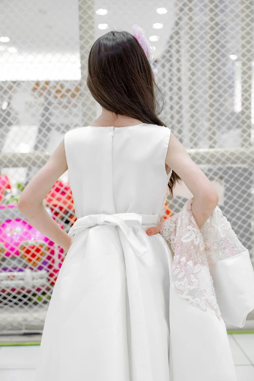 فستان بناتي لون أبيض ياقة دائرية بدون أكمام مزين بزهور و بوشاح تل منفصل على الكتف و برباط في الخصر