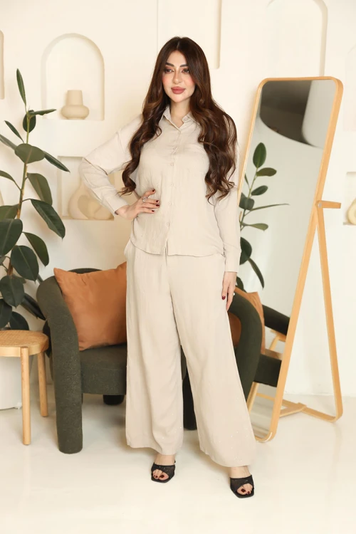 طقم نسائي قطعتين لون بيج قميص بياقة مطوية و أزرار من الأمام و أكمام طويلة مع بنطلون طويل بجيوب من الجانبين
