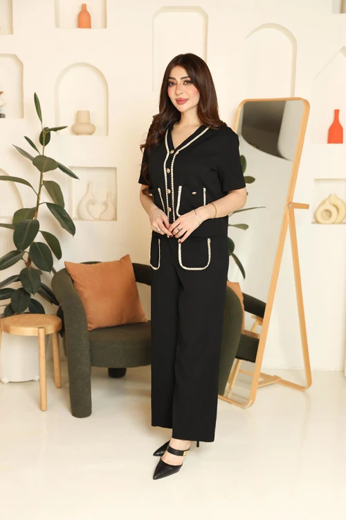 طقم نسائي قطعتين لون أسود مزين بحواف باللون البيج بلوزة بياقة قصة سبعة و أزرار من الأمام و أكمام قصيرة مع بنطلون طويل بجيوب من الأمام