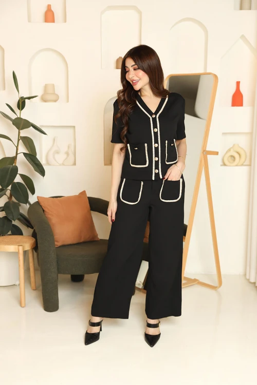 طقم نسائي قطعتين لون أسود مزين بحواف باللون البيج بلوزة بياقة قصة سبعة و أزرار من الأمام و أكمام قصيرة مع بنطلون طويل بجيوب من الأمام