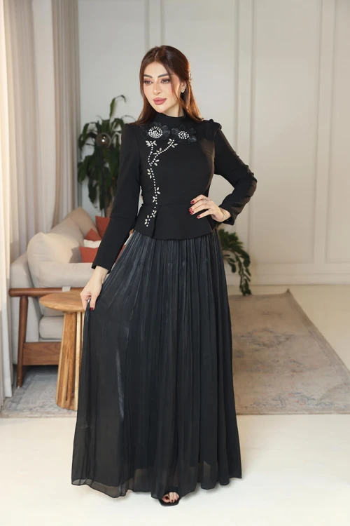 فستان نسائي لون أسود ياقة عالية بأكمام طويلة مزين بتطريزات على شكل زهور بكريستالات من الأمام مع تنورة كسرات