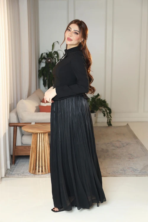 فستان نسائي لون أسود ياقة عالية بأكمام طويلة مزين بتطريزات على شكل زهور بكريستالات من الأمام مع تنورة كسرات