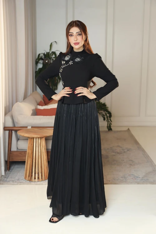 فستان نسائي لون أسود ياقة عالية بأكمام طويلة مزين بتطريزات على شكل زهور بكريستالات من الأمام مع تنورة كسرات