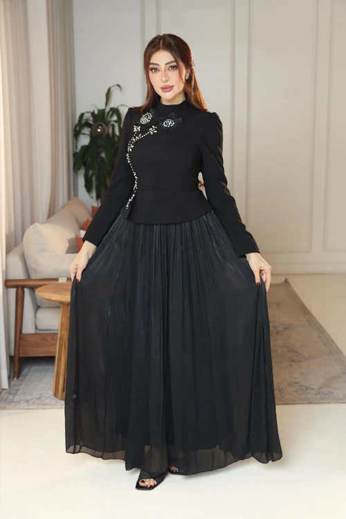 فستان نسائي لون أسود ياقة عالية بأكمام طويلة مزين بتطريزات على شكل زهور بكريستالات من الأمام مع تنورة كسرات