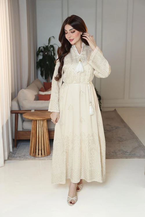 جلابية نسائية لون بيج ياقة عالية بقصة سبعة مزينة بالترتر و تطريزات ذهبية و بأكمام طويلة مع رباط في الخصر