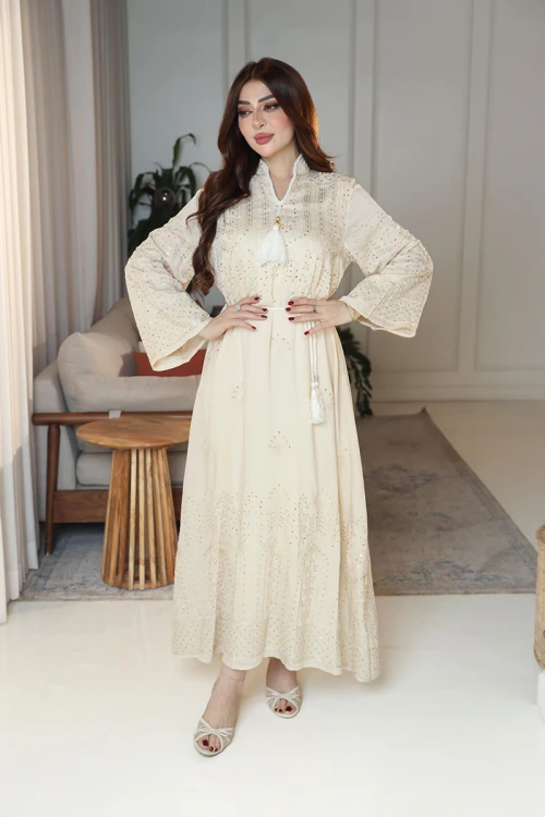 جلابية نسائية لون بيج ياقة عالية بقصة سبعة مزينة بالترتر و تطريزات ذهبية و بأكمام طويلة مع رباط في الخصر