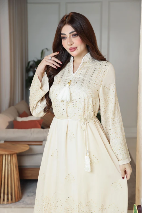 جلابية نسائية لون بيج ياقة عالية بقصة سبعة مزينة بالترتر و تطريزات ذهبية و بأكمام طويلة مع رباط في الخصر