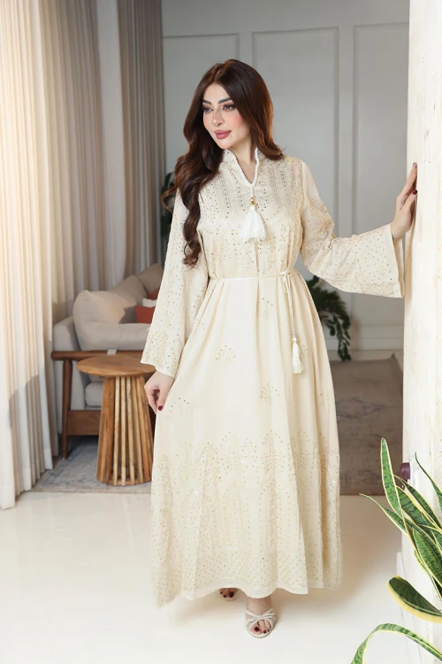 جلابية نسائية لون بيج ياقة عالية بقصة سبعة مزينة بالترتر و تطريزات ذهبية و بأكمام طويلة مع رباط في الخصر