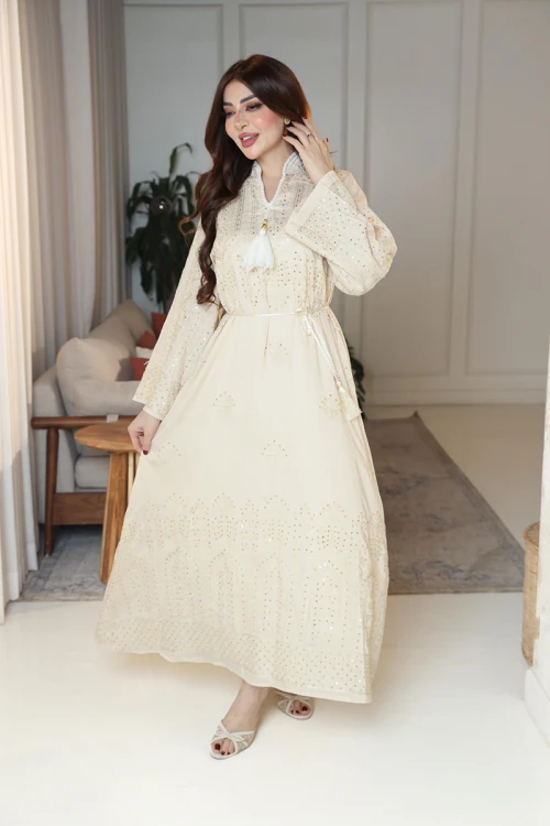 جلابية نسائية لون بيج ياقة عالية بقصة سبعة مزينة بالترتر و تطريزات ذهبية و بأكمام طويلة مع رباط في الخصر