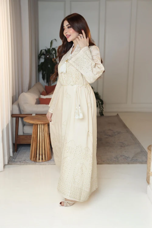 جلابية نسائية لون بيج ياقة عالية بقصة سبعة مزينة بالترتر و تطريزات ذهبية و بأكمام طويلة مع رباط في الخصر