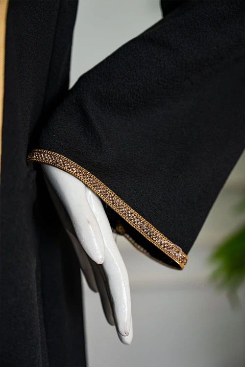 جلابية نسائية لون أسود مزينة خطوط و زهور باللون الذهبي ياقة بقصة سبعة بكلفة مطرزة من الياقة و أطراف الأكمام