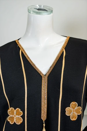 جلابية نسائية لون أسود مزينة خطوط و زهور باللون الذهبي ياقة بقصة سبعة بكلفة مطرزة من الياقة و أطراف الأكمام 