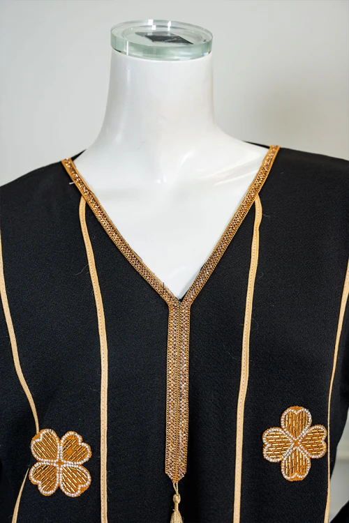 جلابية نسائية لون أسود مزينة خطوط و زهور باللون الذهبي ياقة بقصة سبعة بكلفة مطرزة من الياقة و أطراف الأكمام