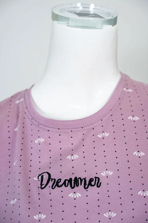 بيجاما نسائية قطعتين لون وردي منقطة باللون الأسود بلوزة بياقة دائرية مزينة بكتابات من الأمام و بأكمام قصيرة مع بنطلون طويل