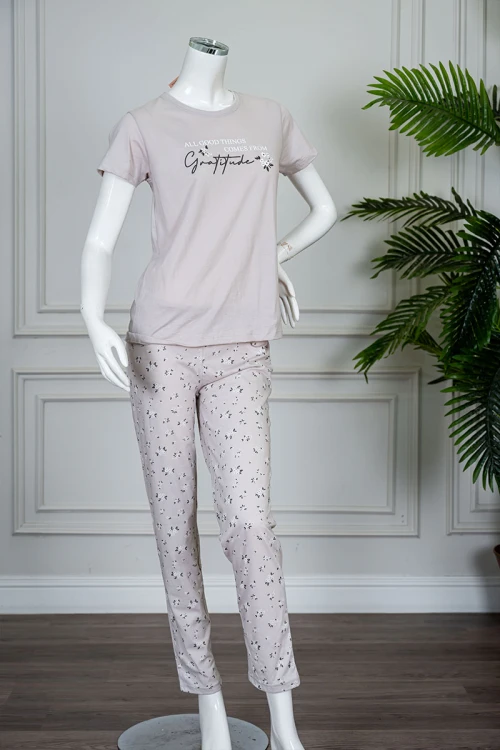 بيجاما نسائية قطعتين لون بيج فاتح بلوزة بياقة دائرية مزينة بكتابات من الأمام و بأكمام قصيرة مع بنطلون طويل مشجر