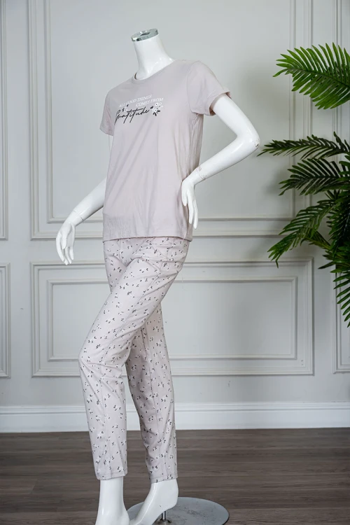 بيجاما نسائية قطعتين لون بيج فاتح بلوزة بياقة دائرية مزينة بكتابات من الأمام و بأكمام قصيرة مع بنطلون طويل مشجر