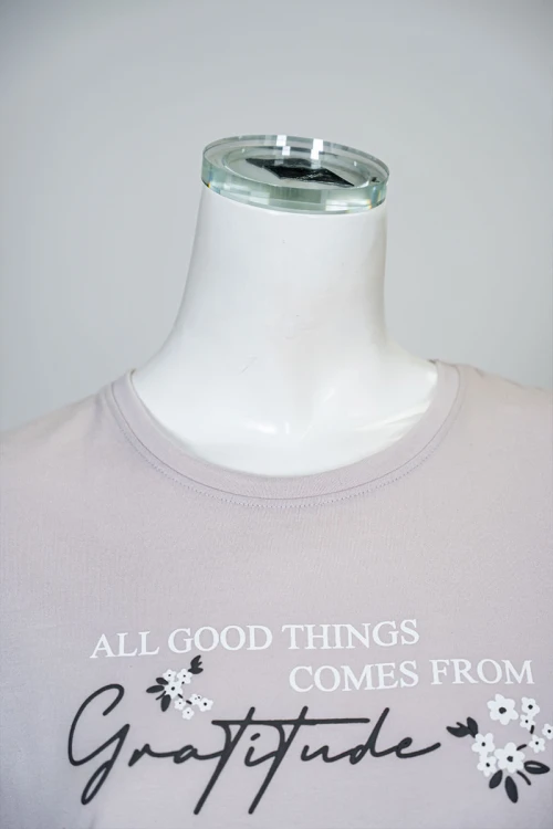 بيجاما نسائية قطعتين لون بيج فاتح بلوزة بياقة دائرية مزينة بكتابات من الأمام و بأكمام قصيرة مع بنطلون طويل مشجر