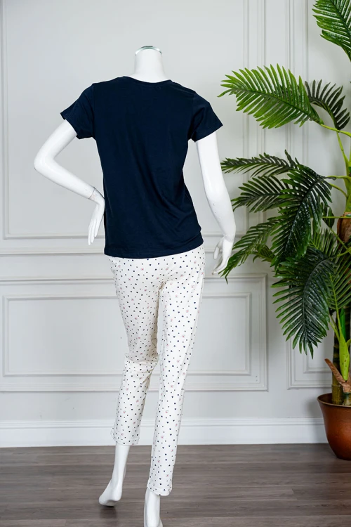 بيجاما نسائية قطعتين بلوزة لون كحلي بياقة دائرية مزينة بكتابات من الأمام و بأكمام قصيرة مع بنطلون اوف وايت طويل مزين بالقلوب