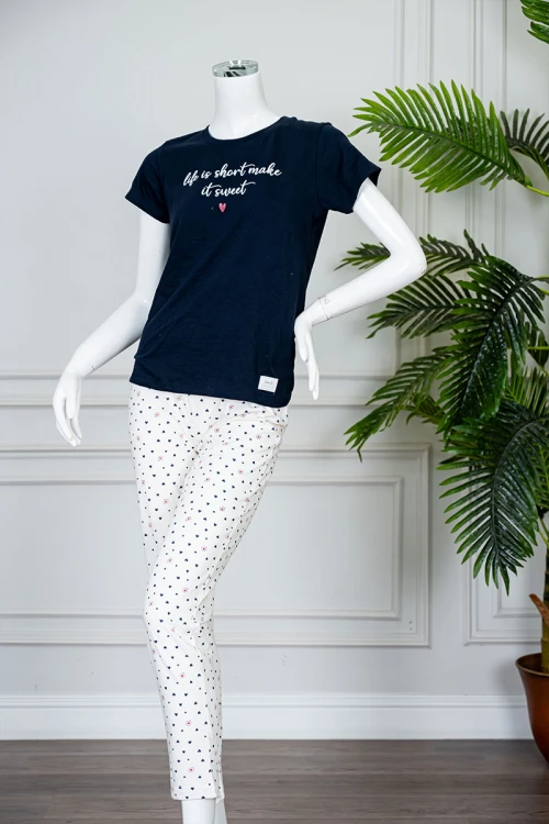 بيجاما نسائية قطعتين بلوزة لون كحلي بياقة دائرية مزينة بكتابات من الأمام و بأكمام قصيرة مع بنطلون اوف وايت طويل مزين بالقلوب