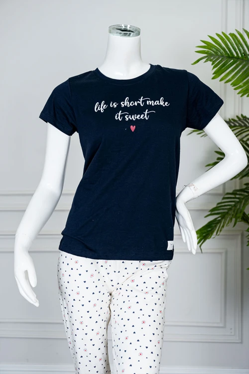 بيجاما نسائية قطعتين بلوزة لون كحلي بياقة دائرية مزينة بكتابات من الأمام و بأكمام قصيرة مع بنطلون اوف وايت طويل مزين بالقلوب