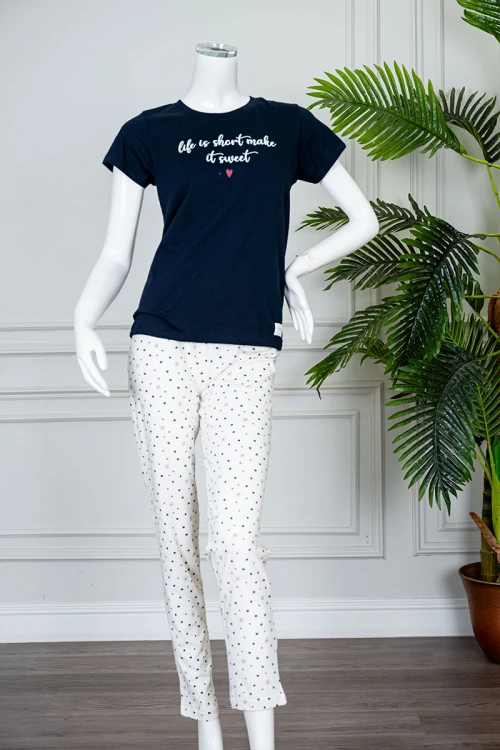 بيجاما نسائية قطعتين بلوزة لون كحلي بياقة دائرية مزينة بكتابات من الأمام و بأكمام قصيرة مع بنطلون اوف وايت طويل مزين بالقلوب