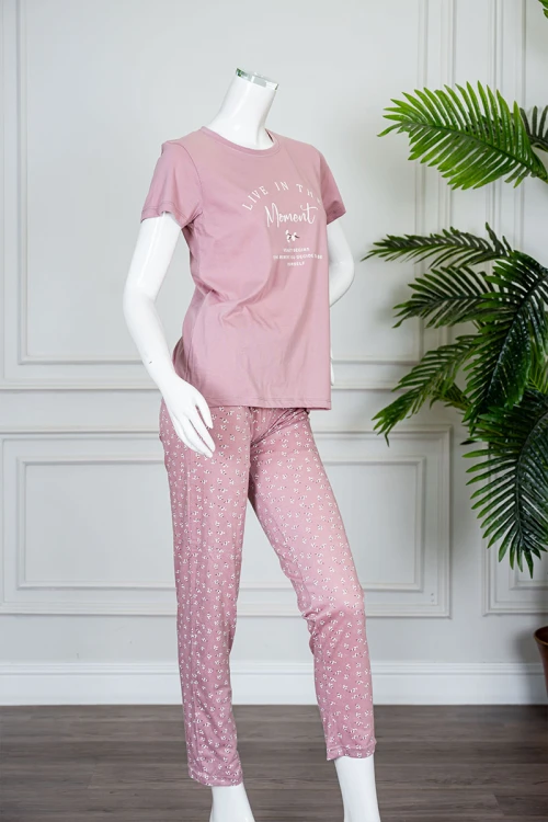 بيجاما نسائية قطعتين لون وردي بلوزة بياقة دائرية مزينة بكتابات من الأمام و بأكمام قصيرة مع بنطلون طويل مشجر