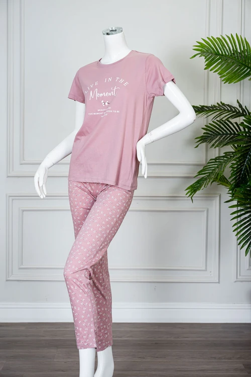 بيجاما نسائية قطعتين لون وردي بلوزة بياقة دائرية مزينة بكتابات من الأمام و بأكمام قصيرة مع بنطلون طويل مشجر