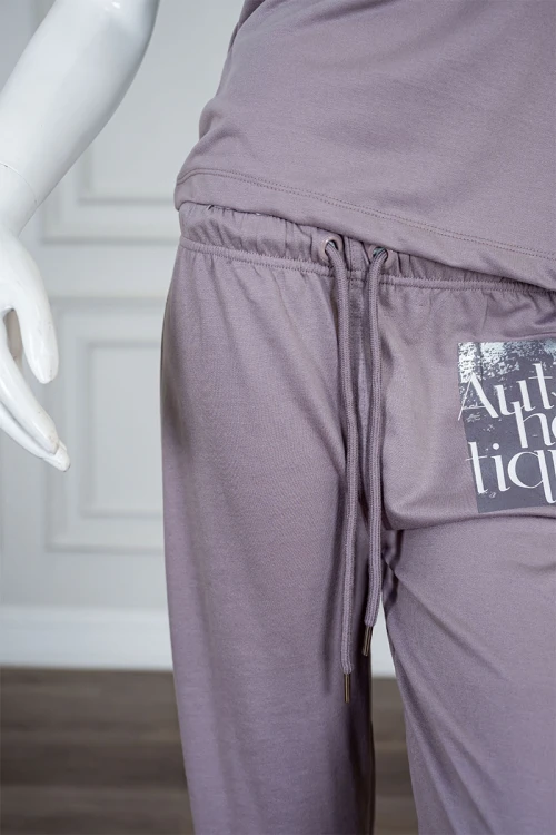 بيجاما نسائية قطعتين لون بنفسجي فاتح مزينة بكتابات من الأمام بلوزة بياقة دائرية و بأكمام قصيرة مع بنطلون طويل برباط في الخصر