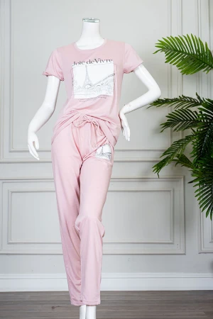 بيجاما نسائية قطعتين لون وردي بلوزة بياقة دائرية مزينة برسومات و كتابات من الأمام بأكمام قصيرة مع بنطلون طويل برباط في الخصر 