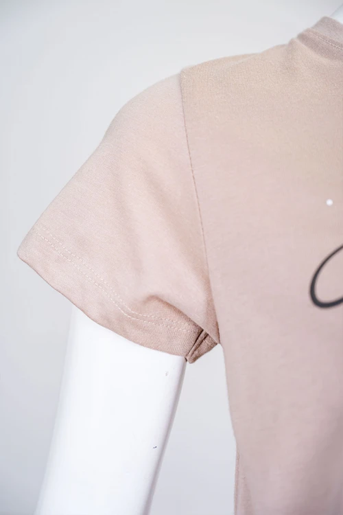 بيجاما نسائية قطعتين لون بيج بلوزة بياقة دائرية مزينة برسومات و كتابات من الأمام بأكمام قصيرة مع بنطلون مشجر