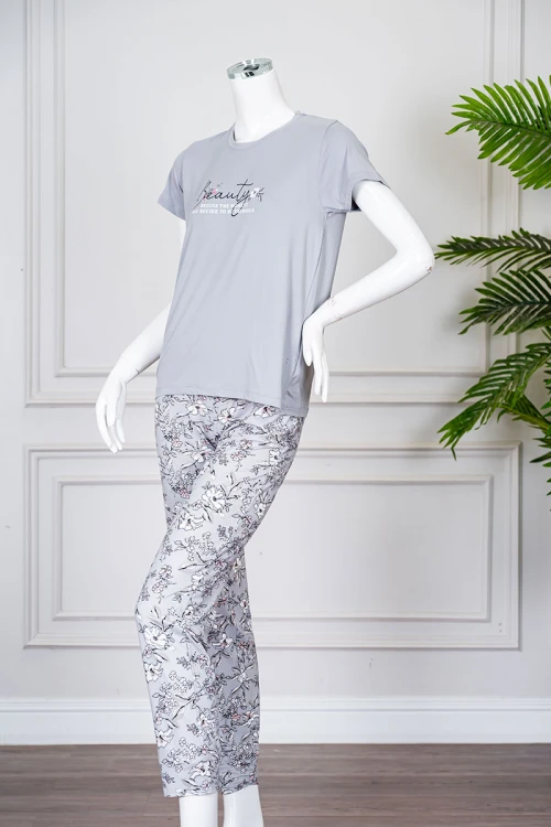 بيجاما نسائية قطعتين لون رمادي بلوزة بياقة دائرية مزينة برسومات و كتابات من الأمام بأكمام قصيرة مع بنطلون مشجر