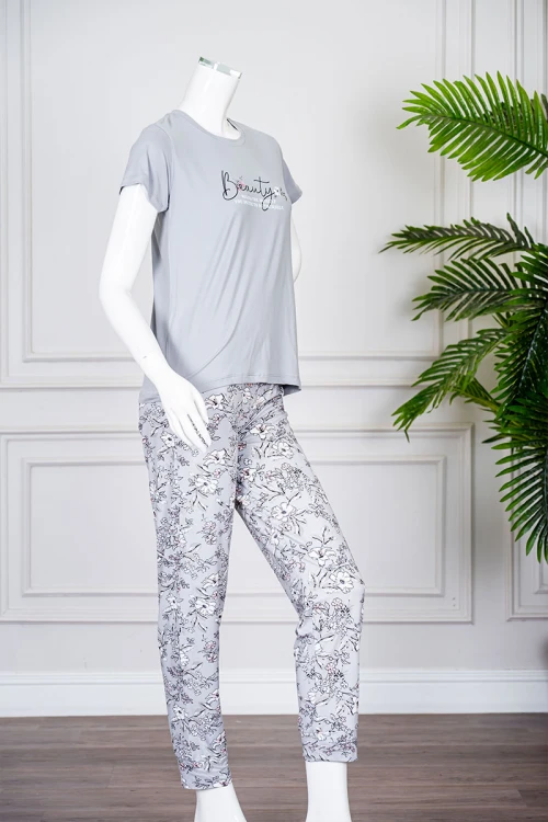 بيجاما نسائية قطعتين لون رمادي بلوزة بياقة دائرية مزينة برسومات و كتابات من الأمام بأكمام قصيرة مع بنطلون مشجر