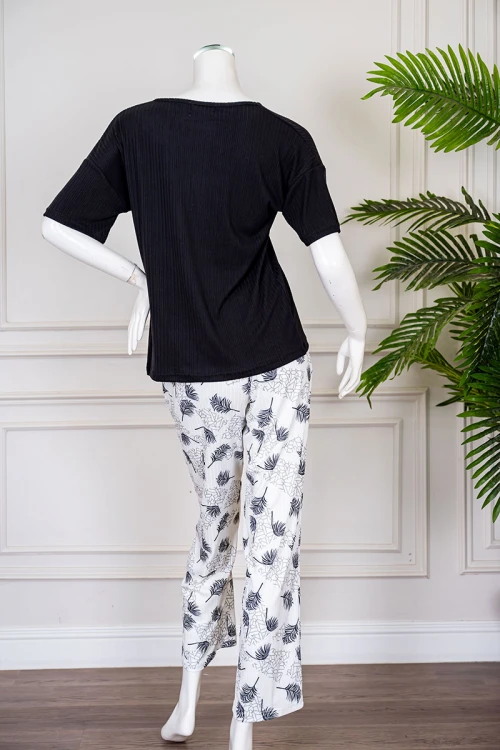 بيجاما نسائية قطعتين لون أسود بلوزة بياقة دائرية مزينة برسومات و كتابات من الأمام بأكمام قصيرة مع بنطلون أبيض مشجر