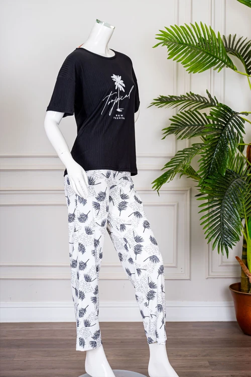 بيجاما نسائية قطعتين لون أسود بلوزة بياقة دائرية مزينة برسومات و كتابات من الأمام بأكمام قصيرة مع بنطلون أبيض مشجر