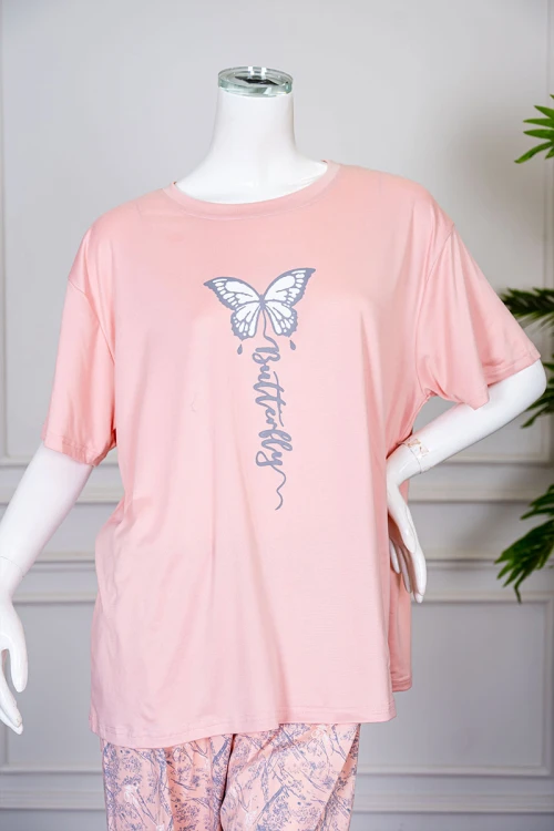 بيجاما نسائية قطعتين لون خربزي بلوزة بياقة دائرية مزينة برسومات و كتابات من الأمام بأكمام قصيرة مع بنطلون مشجر