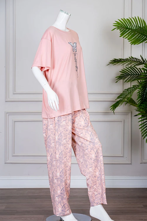 بيجاما نسائية قطعتين لون خربزي بلوزة بياقة دائرية مزينة برسومات و كتابات من الأمام بأكمام قصيرة مع بنطلون مشجر
