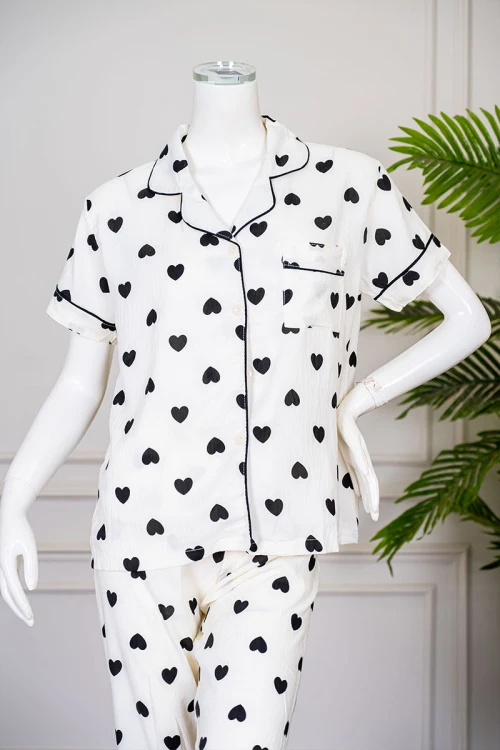 بيجاما نسائية قطعتين لون اوف وايت مزينة بقلوب باللون الأسود  بلوزة بياقة مطوية بجيب من الأمام و أكمام قصيرة مع بنطلون طويل