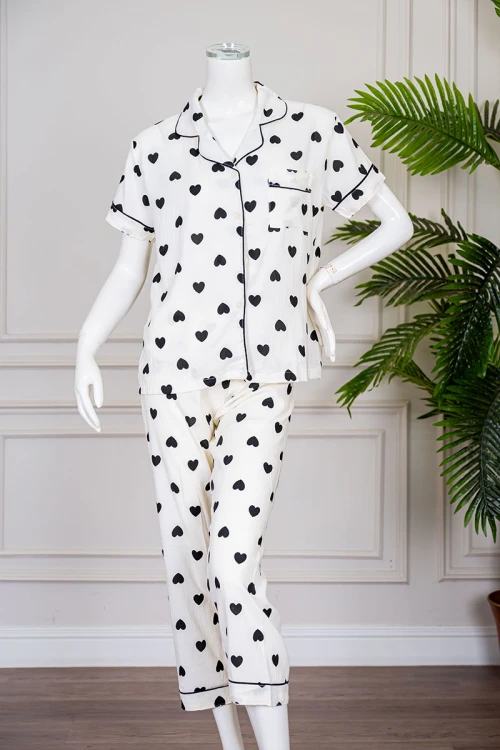 بيجاما نسائية قطعتين لون اوف وايت مزينة بقلوب باللون الأسود  بلوزة بياقة مطوية بجيب من الأمام و أكمام قصيرة مع بنطلون طويل