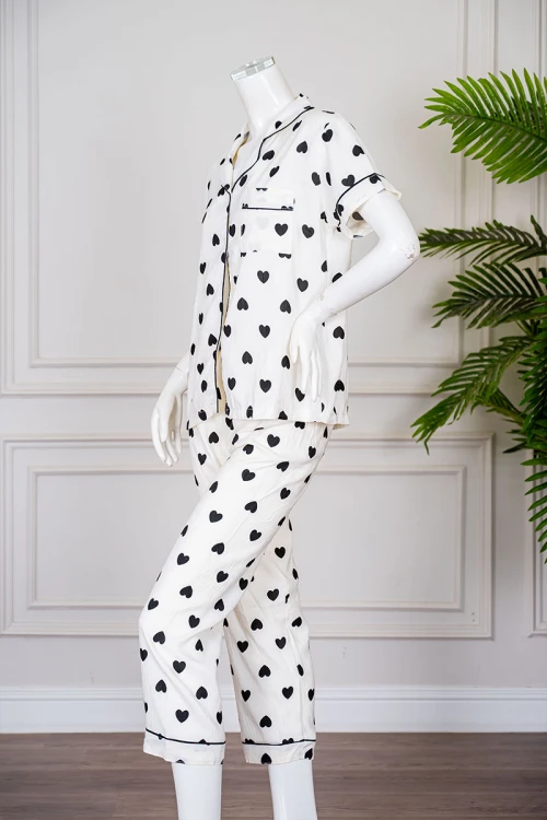 بيجاما نسائية قطعتين لون اوف وايت مزينة بقلوب باللون الأسود  بلوزة بياقة مطوية بجيب من الأمام و أكمام قصيرة مع بنطلون طويل